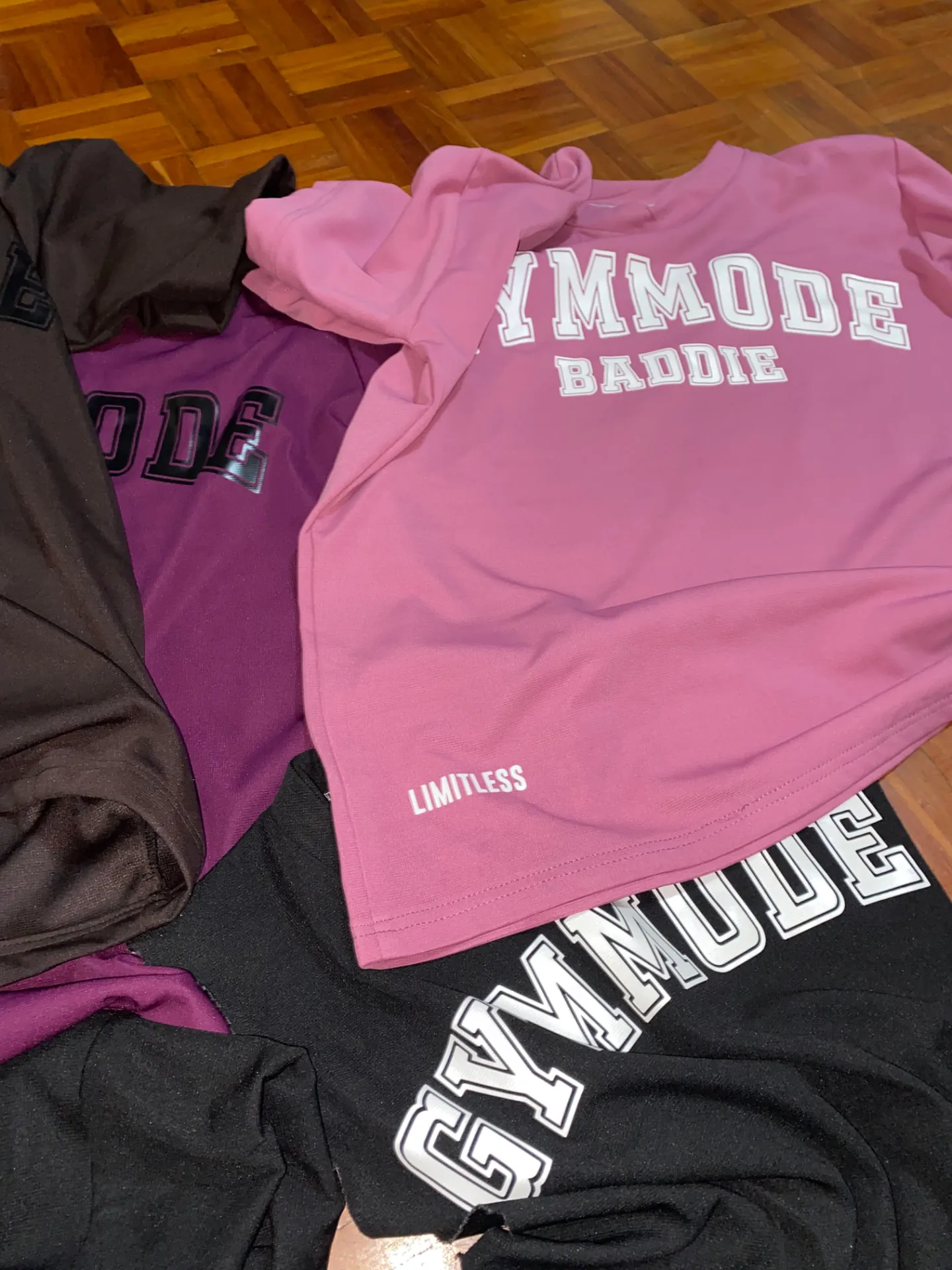 GYMMODE Limitless Edition apparel laid out — pink, burgundy, brown and black pieces